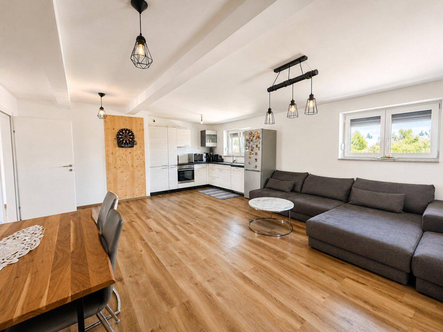Offener Wohn-, Ess- und Küchenbereich mit Laminatboden und modernem Design.