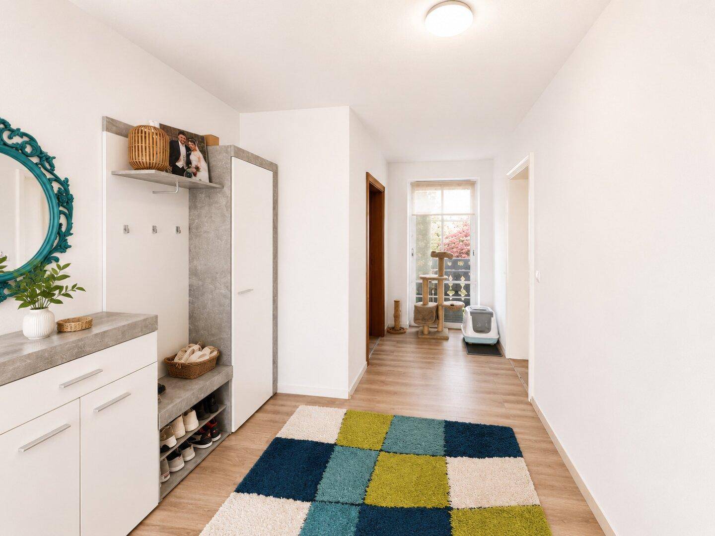 Eingangsbereich mit Garderobe, einem dekorativen Spiegel und einem bunten Teppich auf Laminatboden.