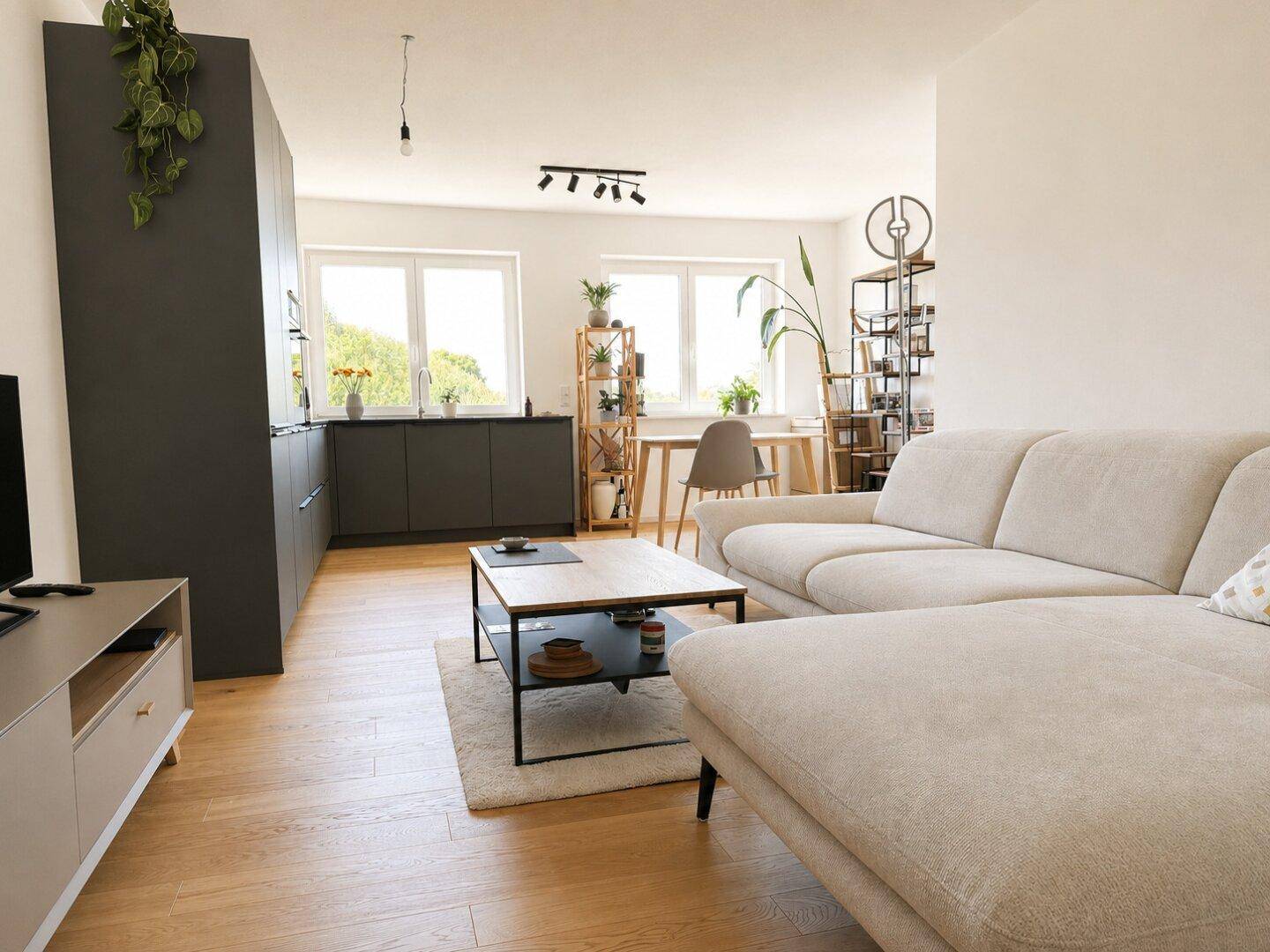 Offener Wohn- und Essbereich mit Holzboden, bequemer Couch und Blick in die Küche.