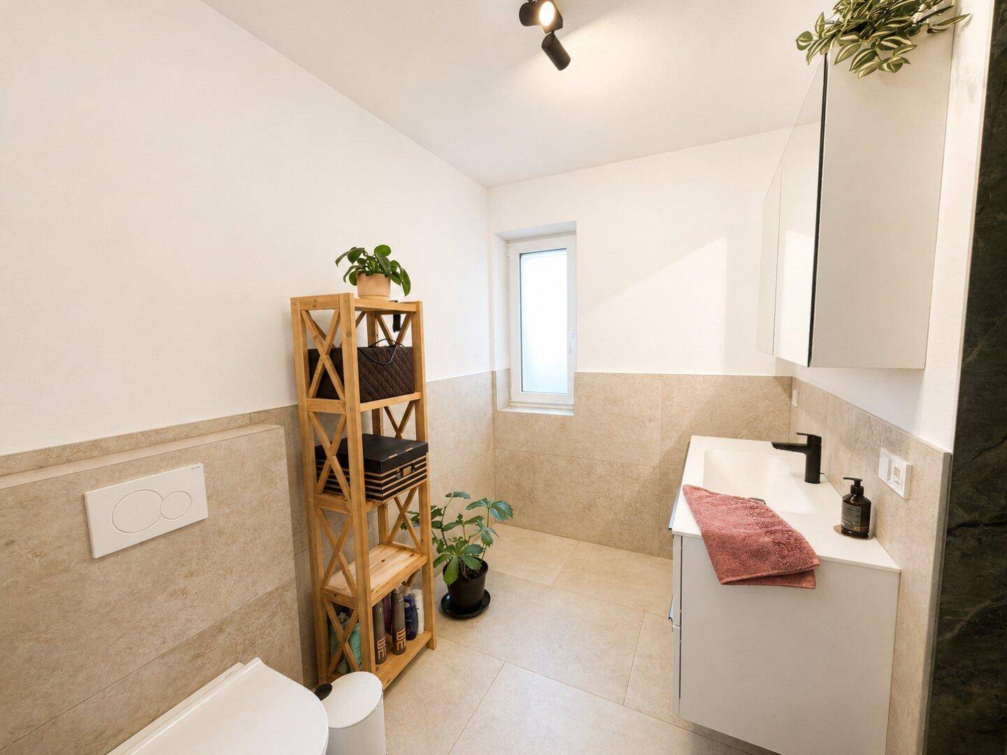 Helles Badezimmer mit Wand-WC, modernem Waschtisch und praktischem Holzregal.