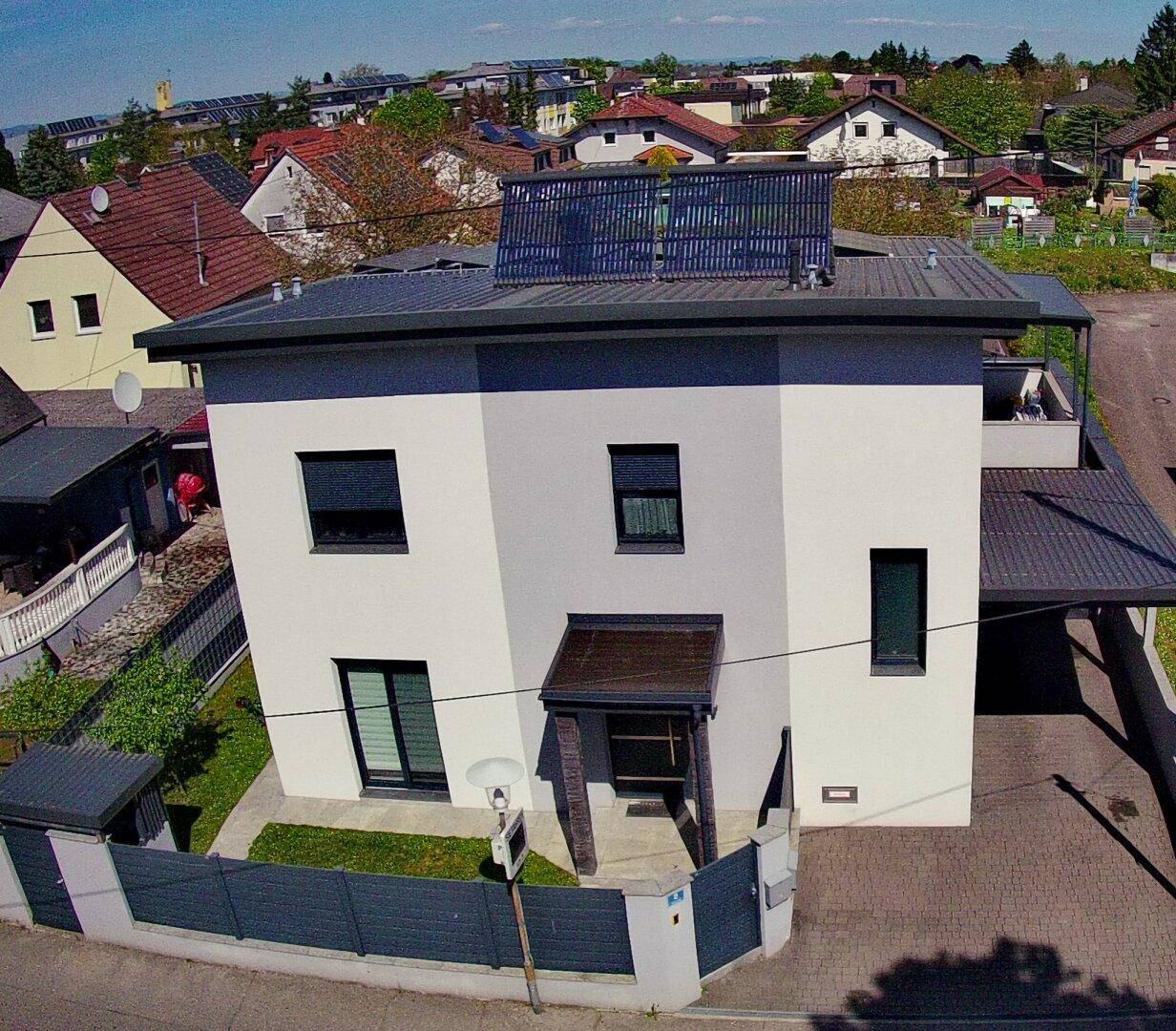 Modernes Einfamilienhaus mit Flachdach, Photovoltaikanlage und Carport in Wohnsiedlung.