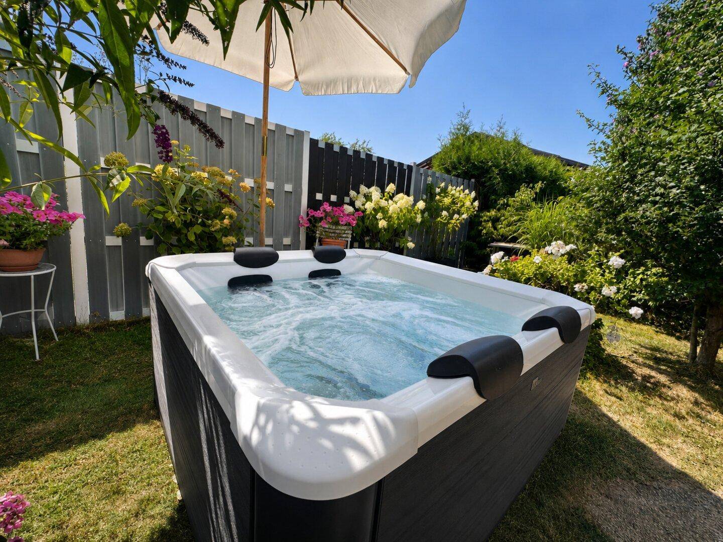 Moderner Whirlpool im Garten unter einem Sonnenschirm, umgeben von üppigem Grün.