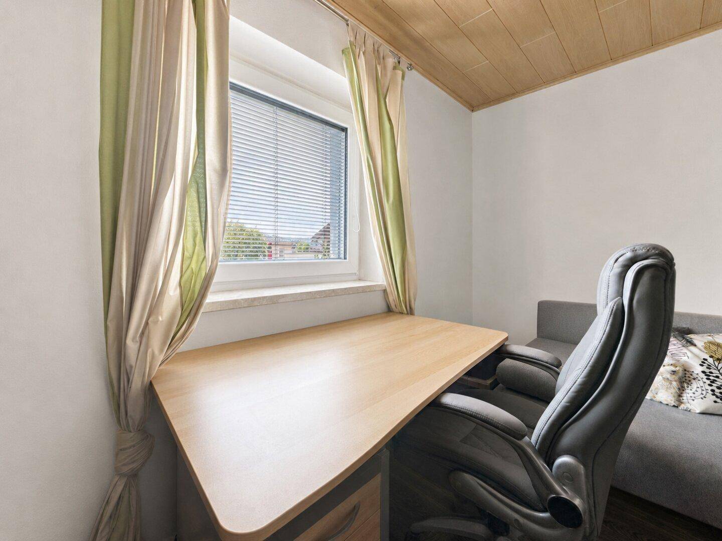 Arbeitsbereich mit Schreibtisch und Bürostuhl am Fenster, ideal für Home-Office.