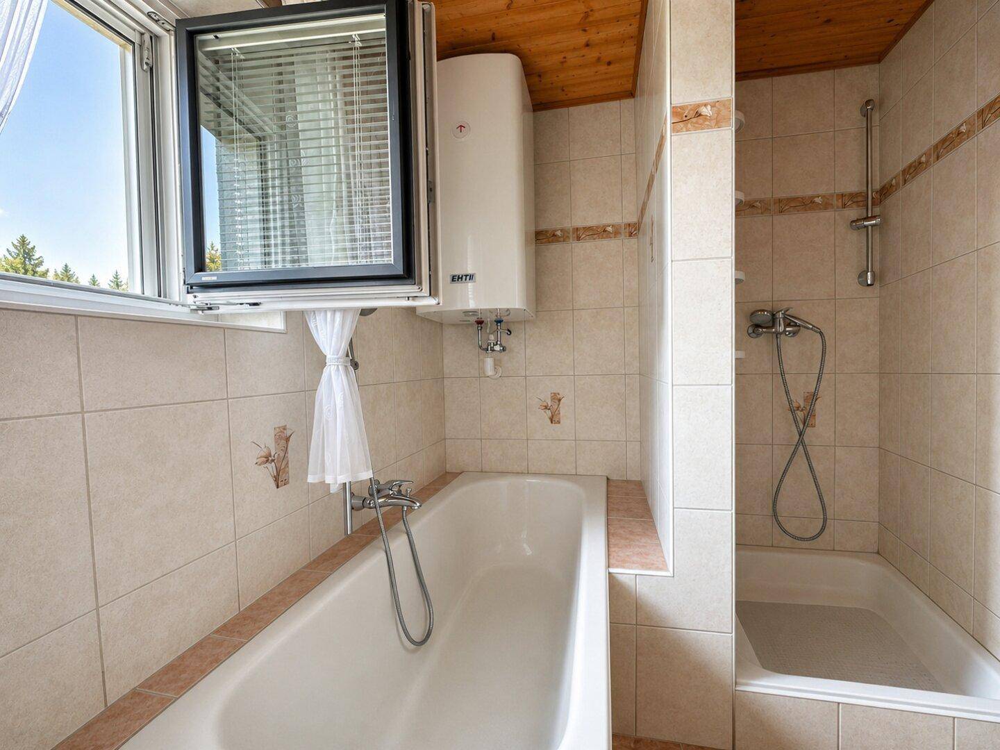 Badezimmer mit Badewanne, Duschvorrichtung und Fenster für Belüftung und Tageslicht.