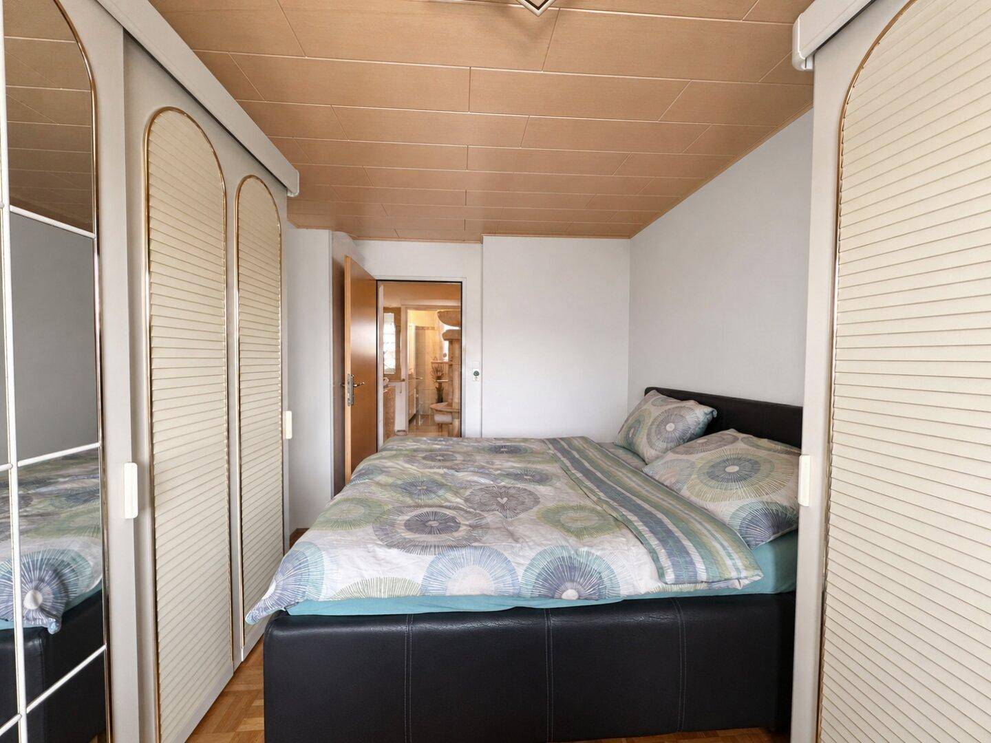 Schlafzimmer mit Doppelbett und integrierten Kleiderschränken, Holzboden.