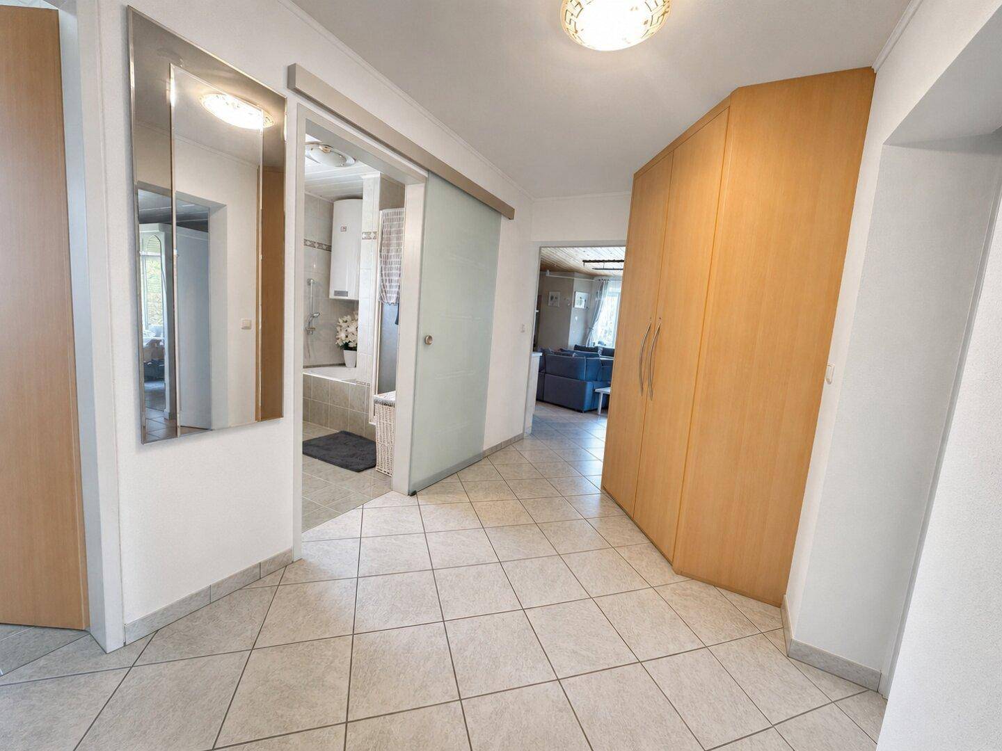 Heller Flur mit Fliesenboden und Einbauschrank, der zum Badezimmer führt.