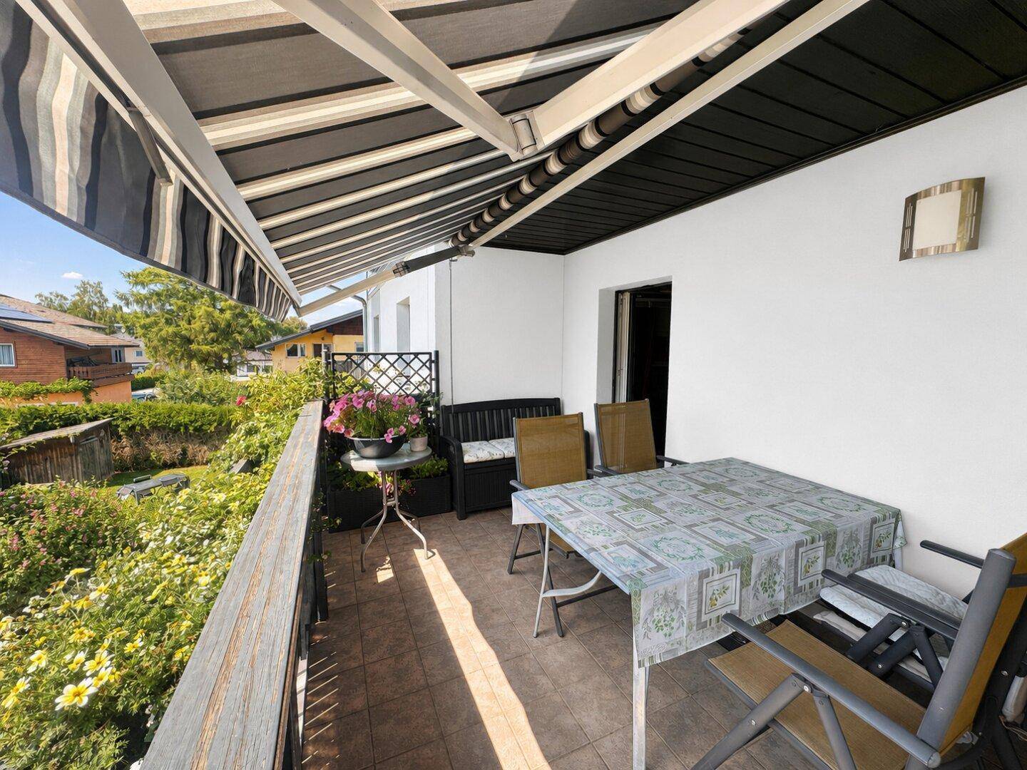 Gemütlicher Balkon mit Markise, Esstisch und Blick ins Grüne.
