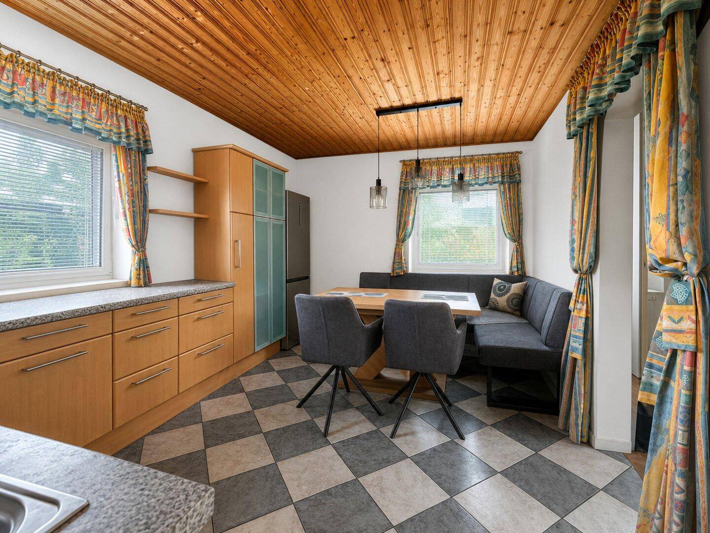 Traditionelle Küche mit Essbereich, Holzdecke und karierten Bodenfliesen.