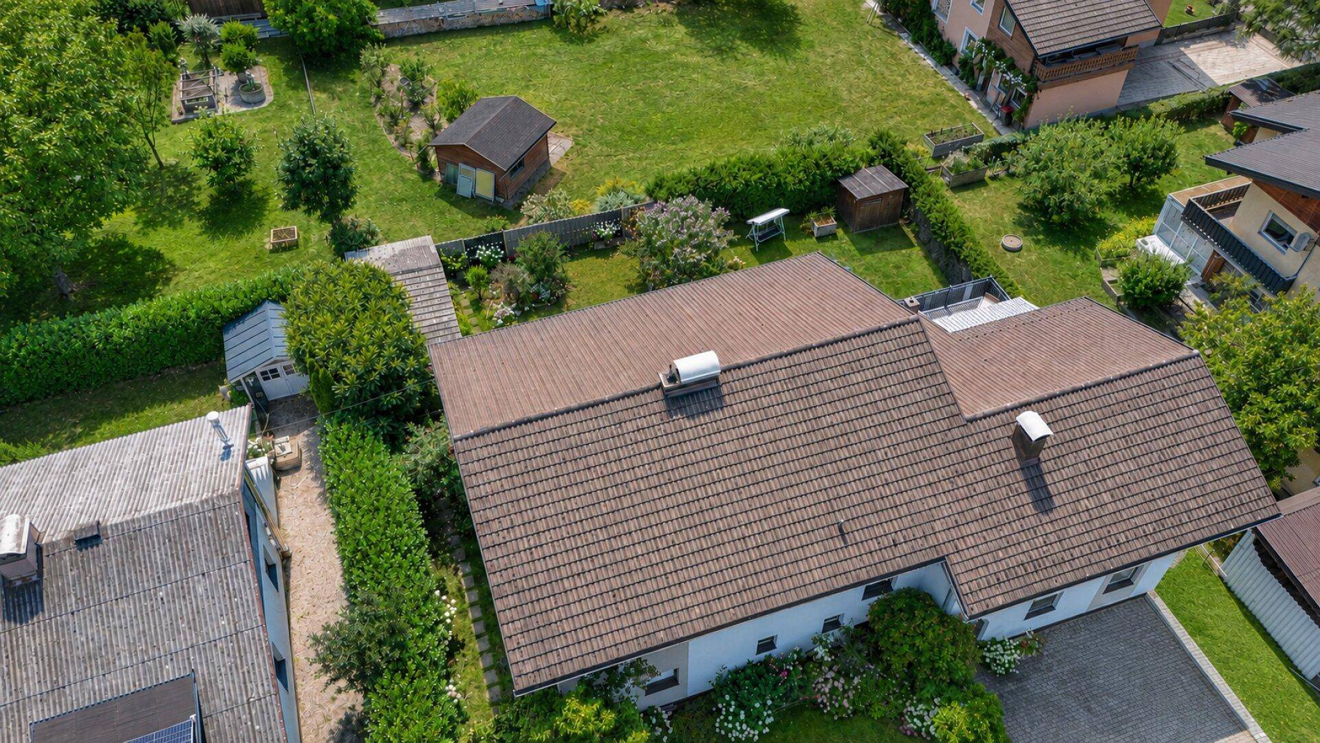 Dachansicht eines Wohnhauses mit Ziegeldach und gepflegtem Gartenbereich.