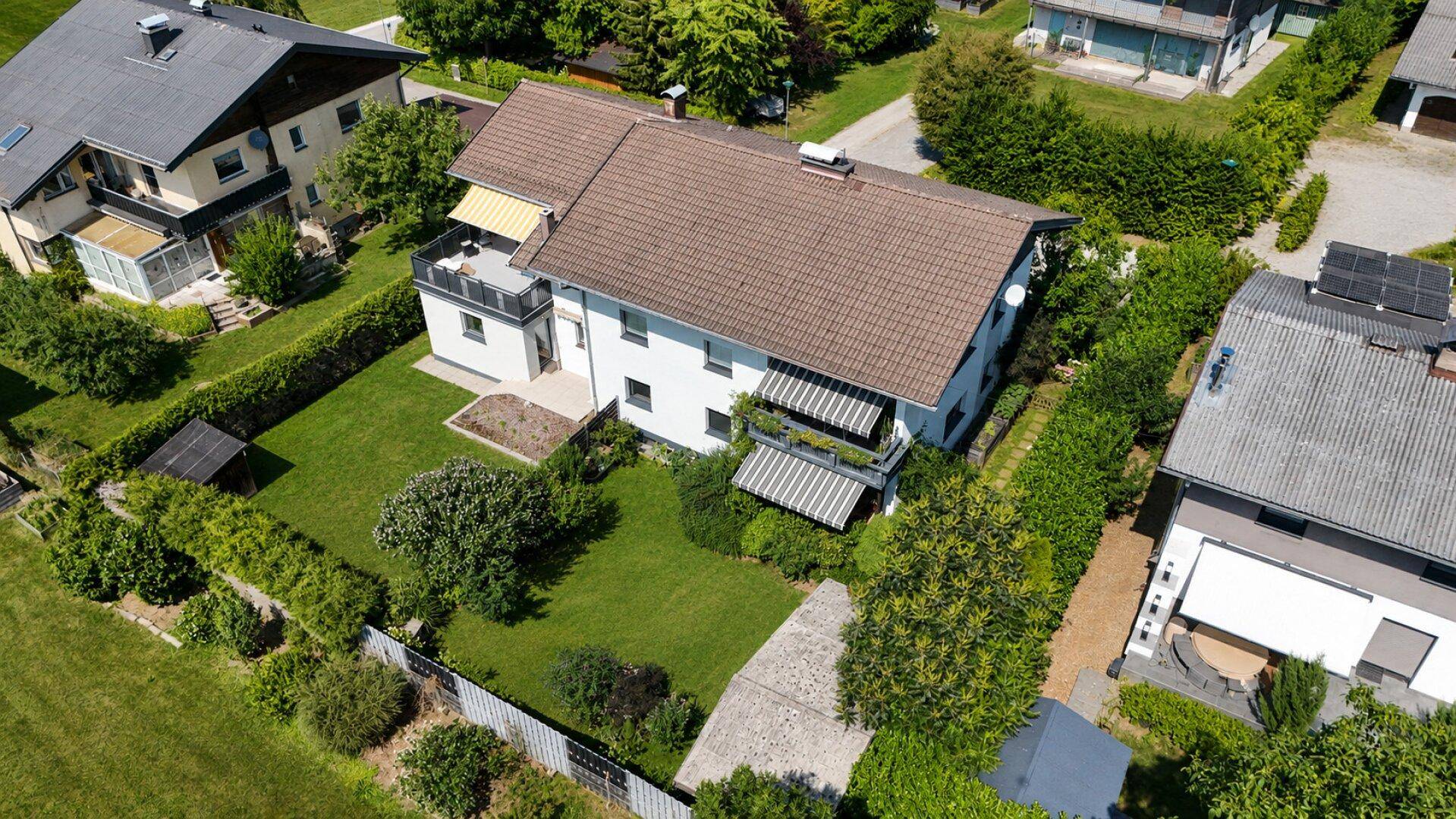 Vogelperspektive eines Hauses mit Garten, Balkon und Terrasse in ländlicher Umgebung.