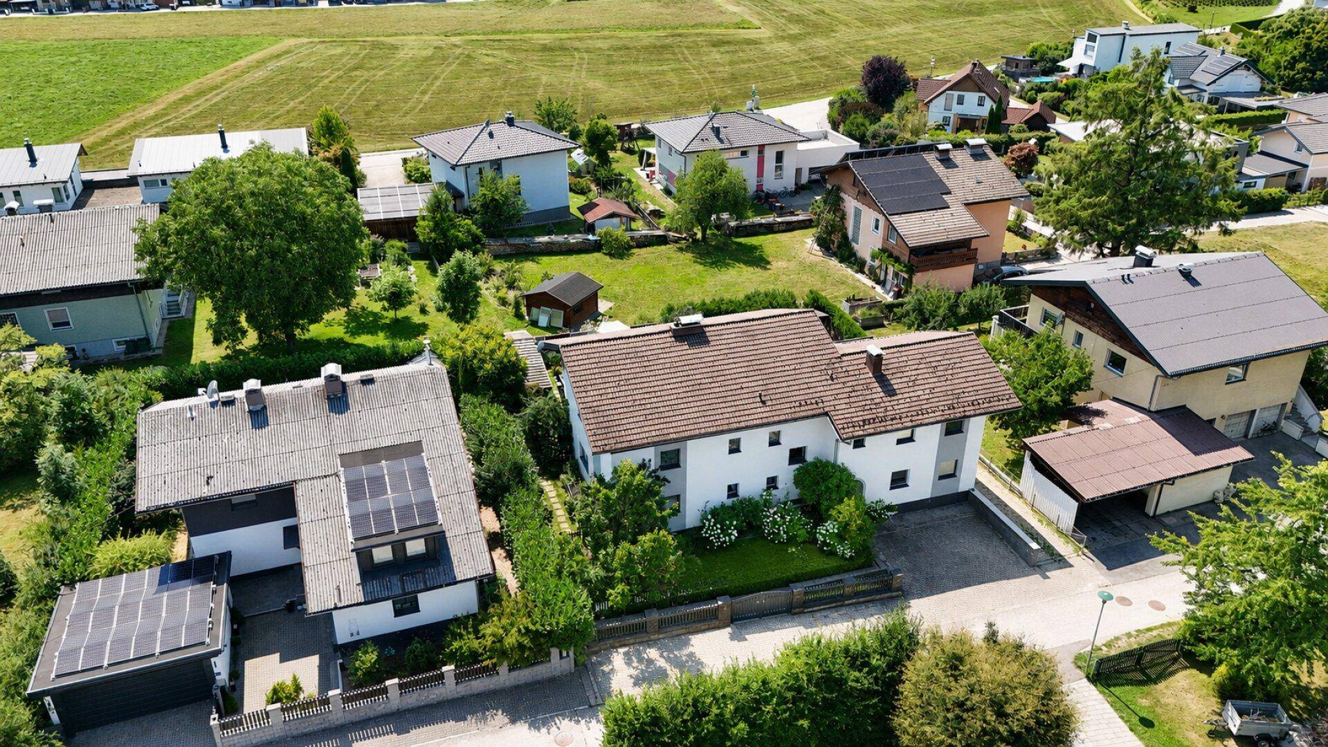 Luftaufnahme einer Wohnsiedlung mit Einfamilienhäusern und umliegenden Grünflächen.