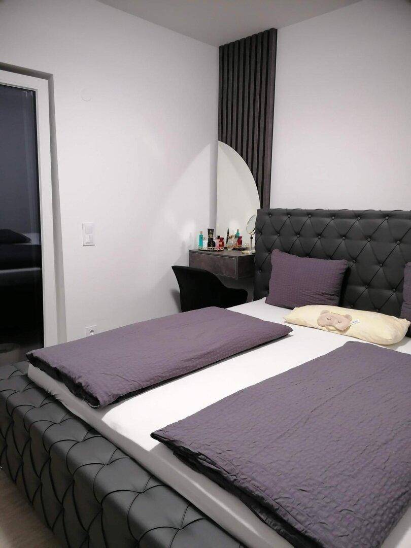 Geräumiges Schlafzimmer mit großem Doppelbett, Schminktisch und dekorativer Wandverkleidung.
