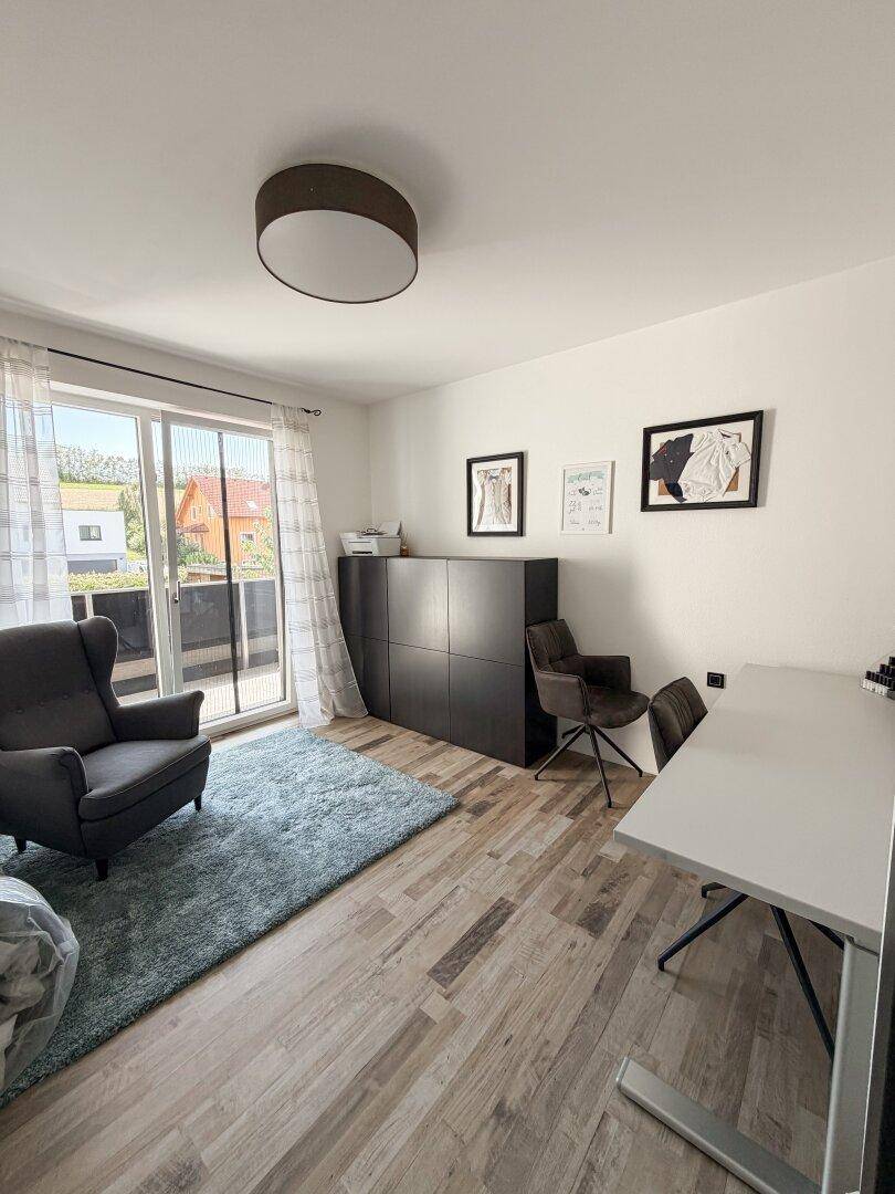 Helles Arbeitszimmer mit Schreibtisch, Sessel und direktem Zugang zu einem Balkon.