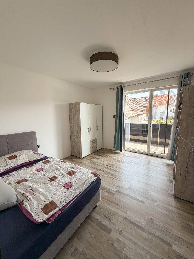 Gemütliches Schlafzimmer mit Bett, Kleiderschrank und direktem Zugang zum Balkon.