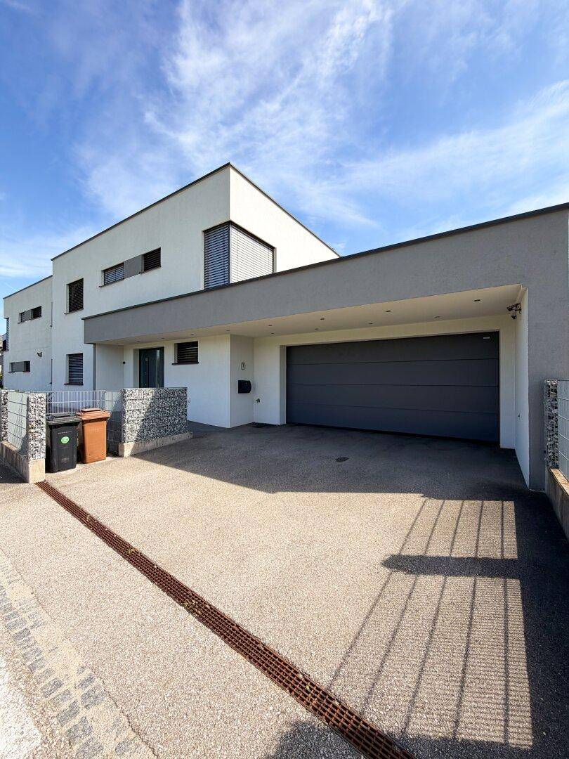 Moderne Hausfront mit integrierter Garage und überdachtem Carport.