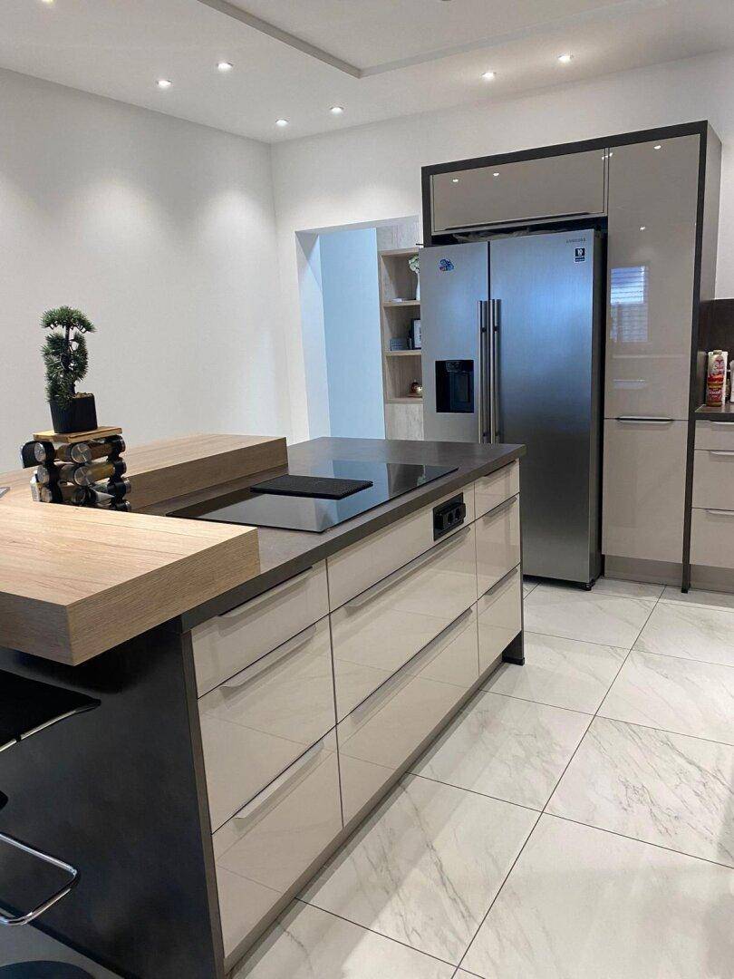 Detailansicht der modernen Kücheninsel mit Induktionskochfeld und integriertem Kühlschrank.