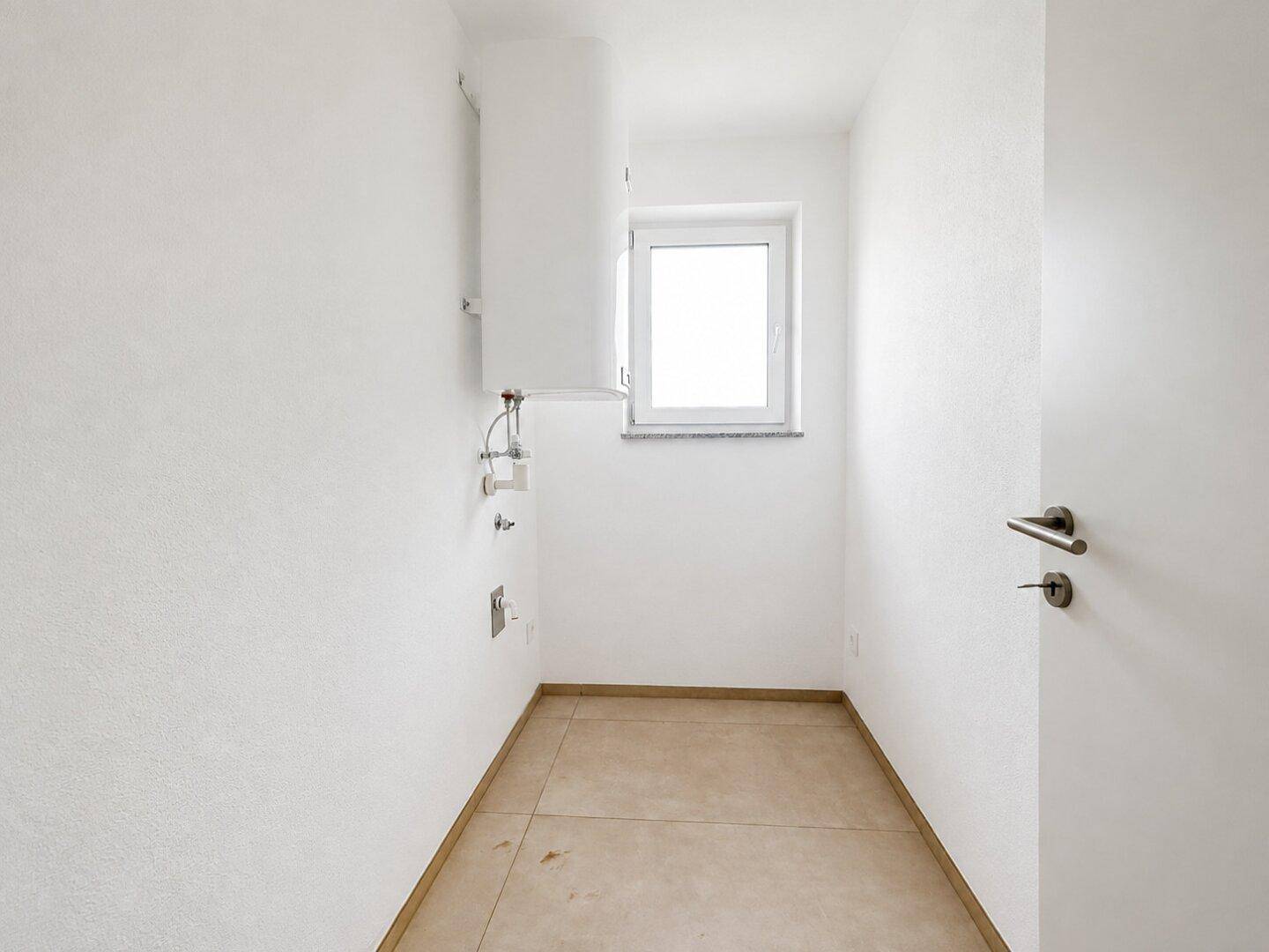 Kleiner Hauswirtschaftsraum mit Fenster, Fliesenboden und Anschlüssen für Geräte.