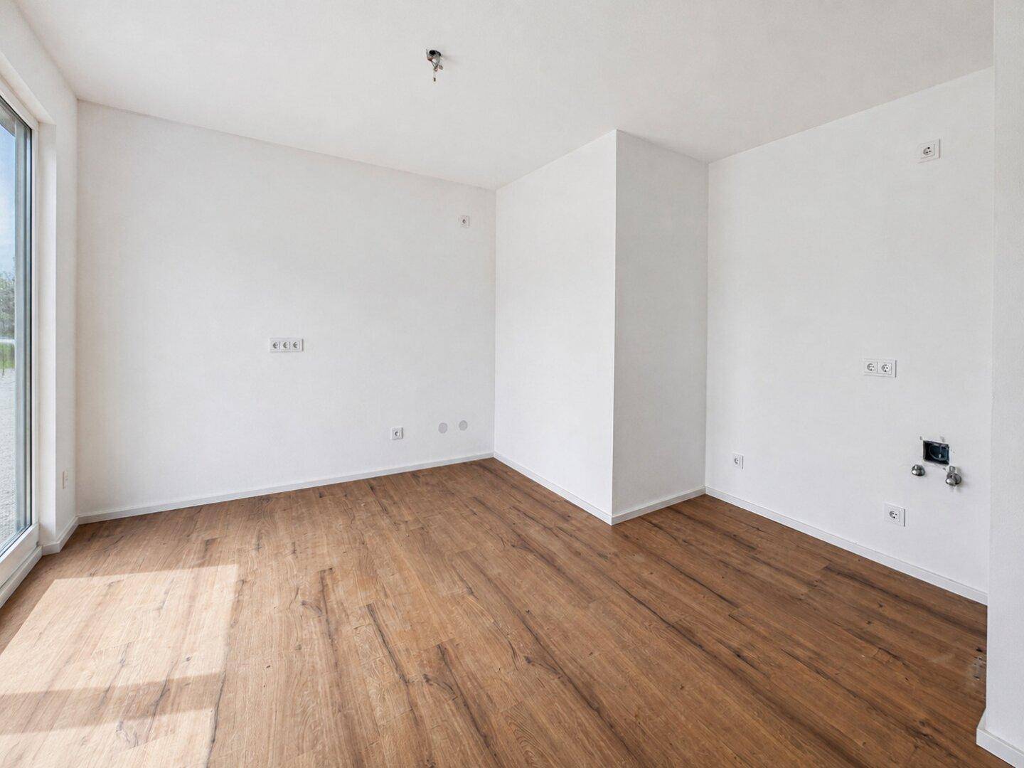 Geräumiger, heller Raum mit Laminatboden und großen Fenstern für viel Tageslicht.