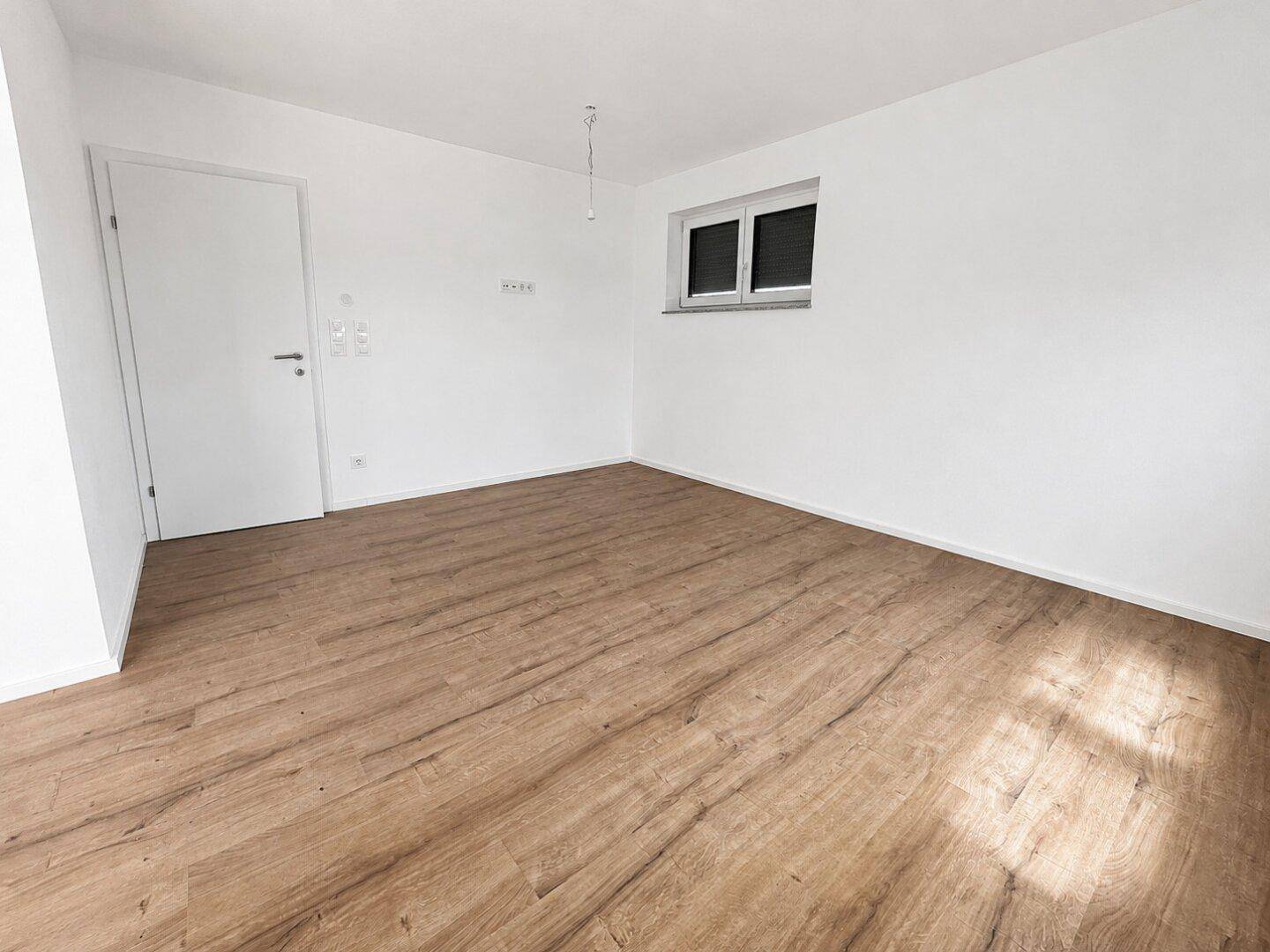 Helles Schlafzimmer mit Laminatboden und weiß gestrichenen Wänden.