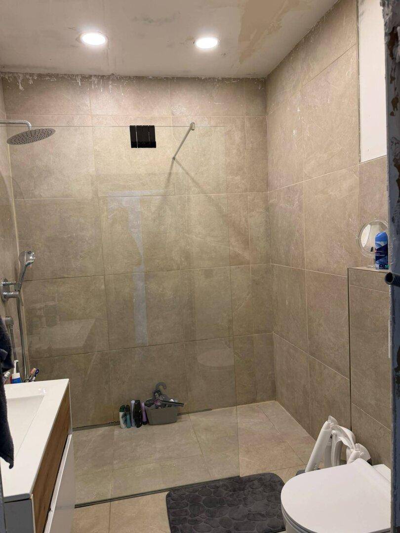 Modernes Badezimmer im Bau mit beigen Fliesen und einer geräumigen begehbaren Dusche.