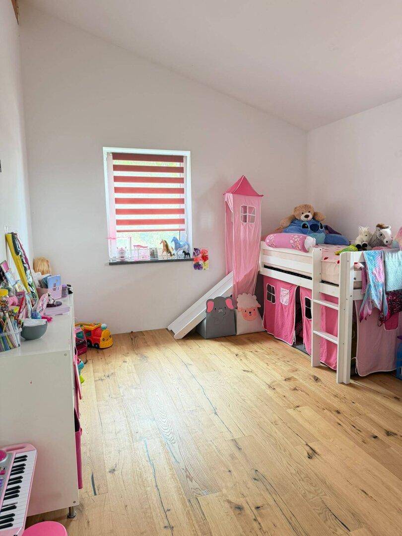 Kinderzimmer mit Holzdielenboden, Hochbett mit Rutsche und schräger Decke.