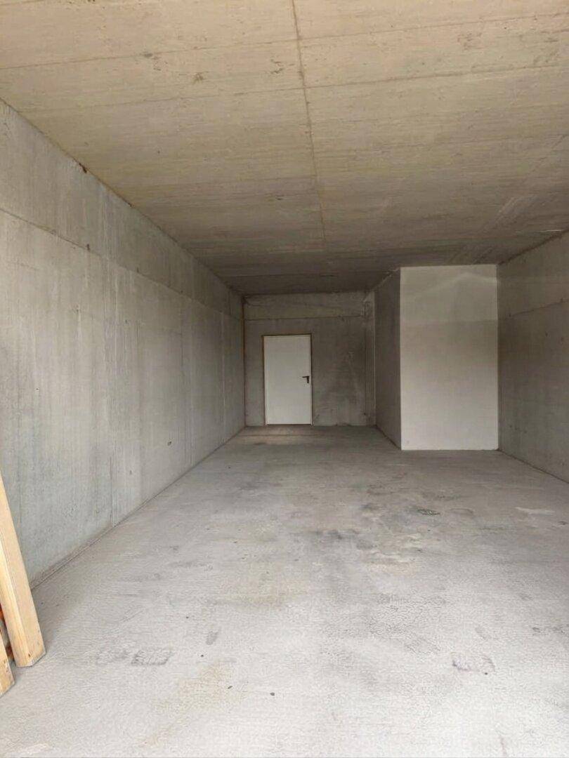 Leerer Kellerraum mit rohen Betonwänden und -boden, bereit für den Ausbau.