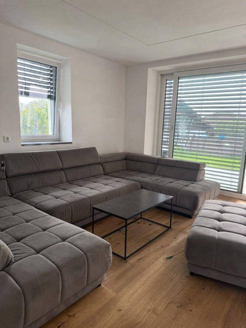 Geräumiges Wohnzimmer mit großem Ecksofa, Holzdielenboden und Zugang zur Terrasse.