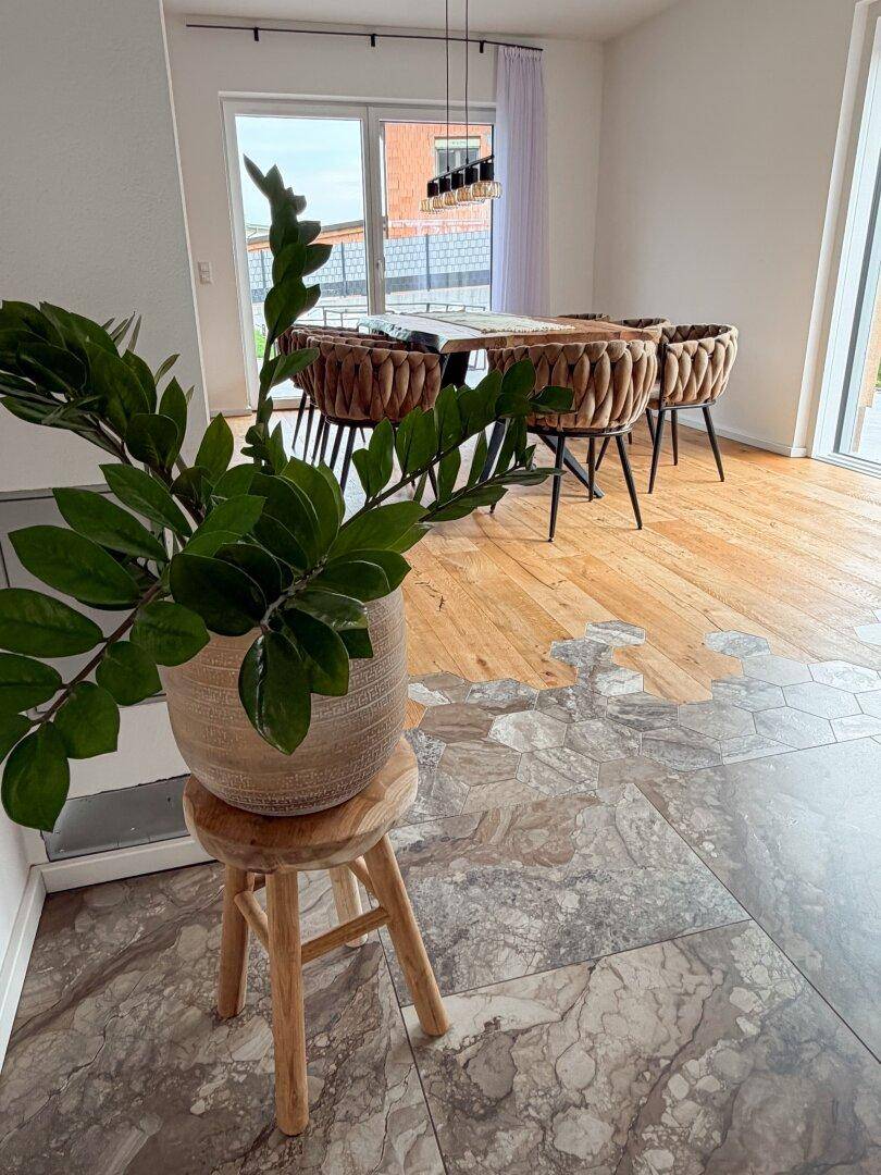 Essbereich mit Holztisch, modernen Stühlen und einer Kombination aus Holz- und Fliesenboden.