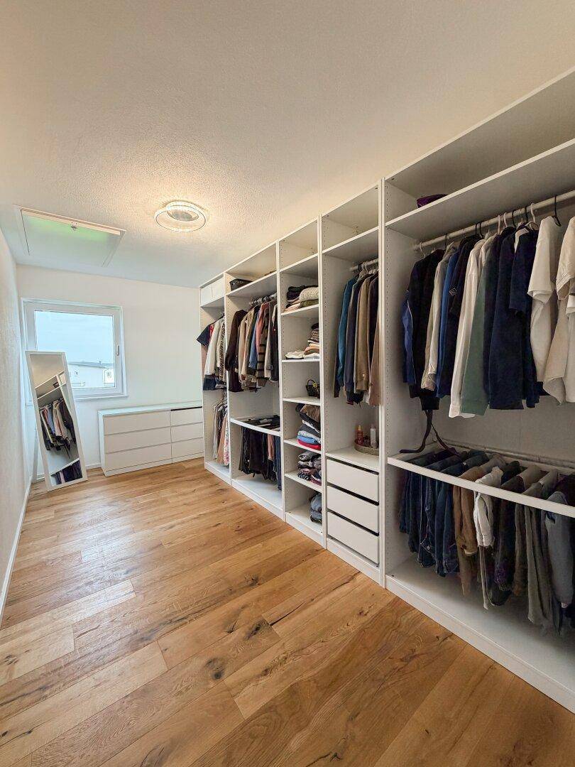 Geräumiger begehbarer Kleiderschrank mit maßgefertigten Regalen und viel Stauraum.