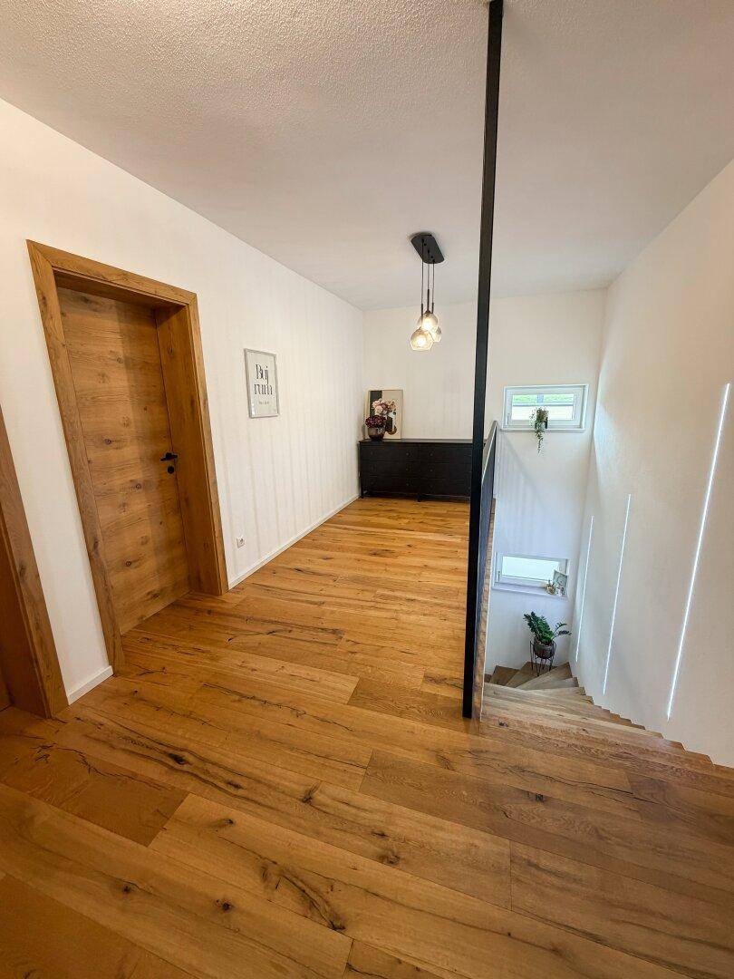 Heller Flur im Obergeschoss mit Holzboden und Blick auf die Treppe.