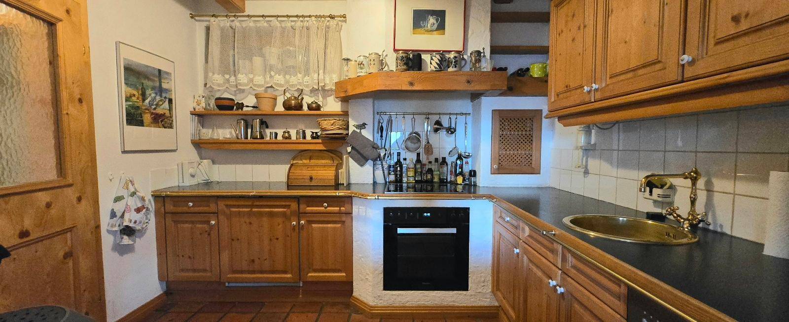 Rustikale Küche mit Holzschränken, integriertem Backofen und traditioneller Einrichtung.
