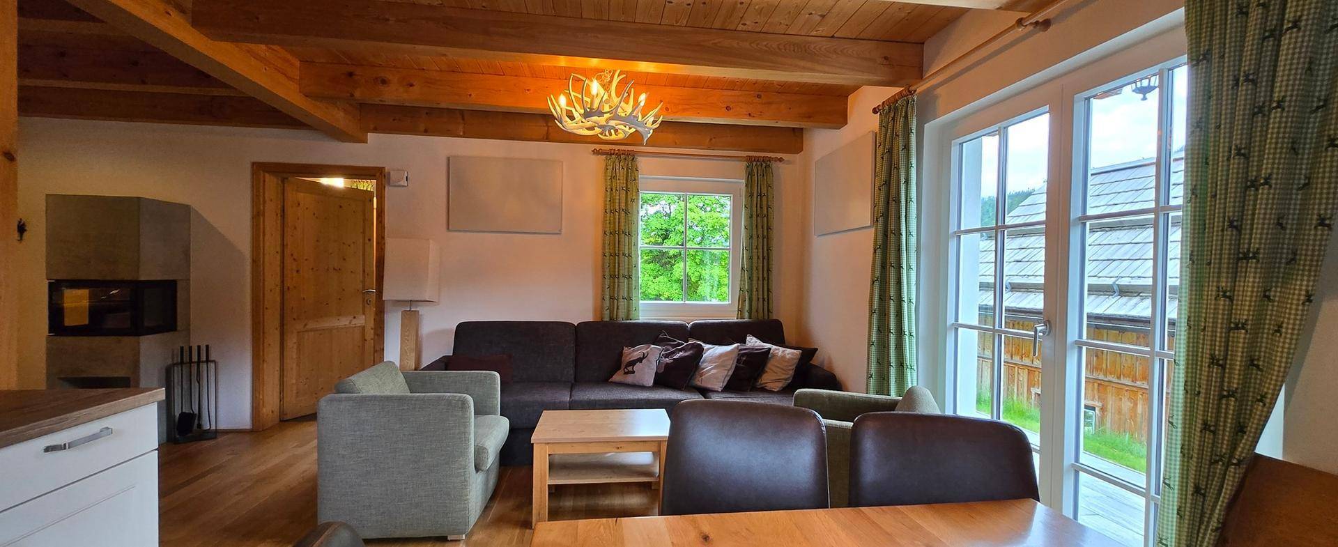 Geräumiger Wohnbereich mit bequemen Sofas, Holzbalken und Zugang zur Terrasse.