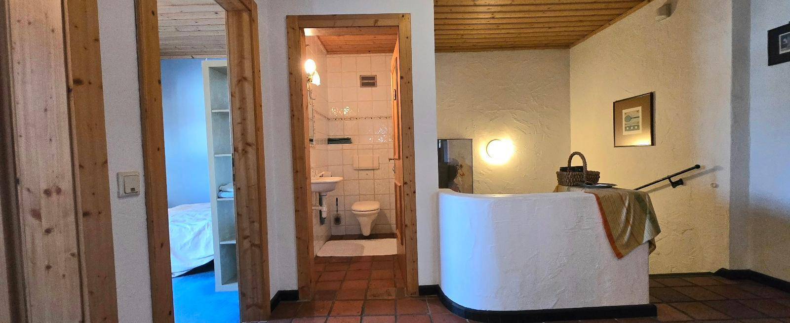 Flur mit Holzdecke und Zugang zu einem separaten Gäste-WC mit Terrakottafliesen.