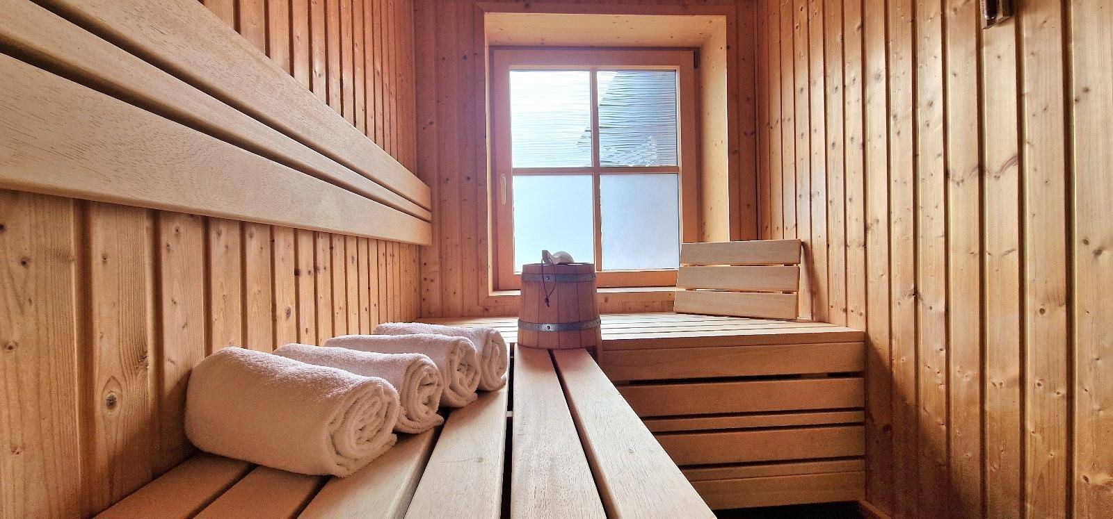 Traditionelle Holzsauna mit Bänken und Fenster für entspannende Momente.