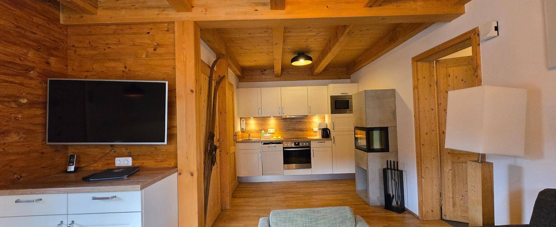 Gemütlicher Wohnbereich mit Holzwänden, integrierter Küche und Kaminofen.