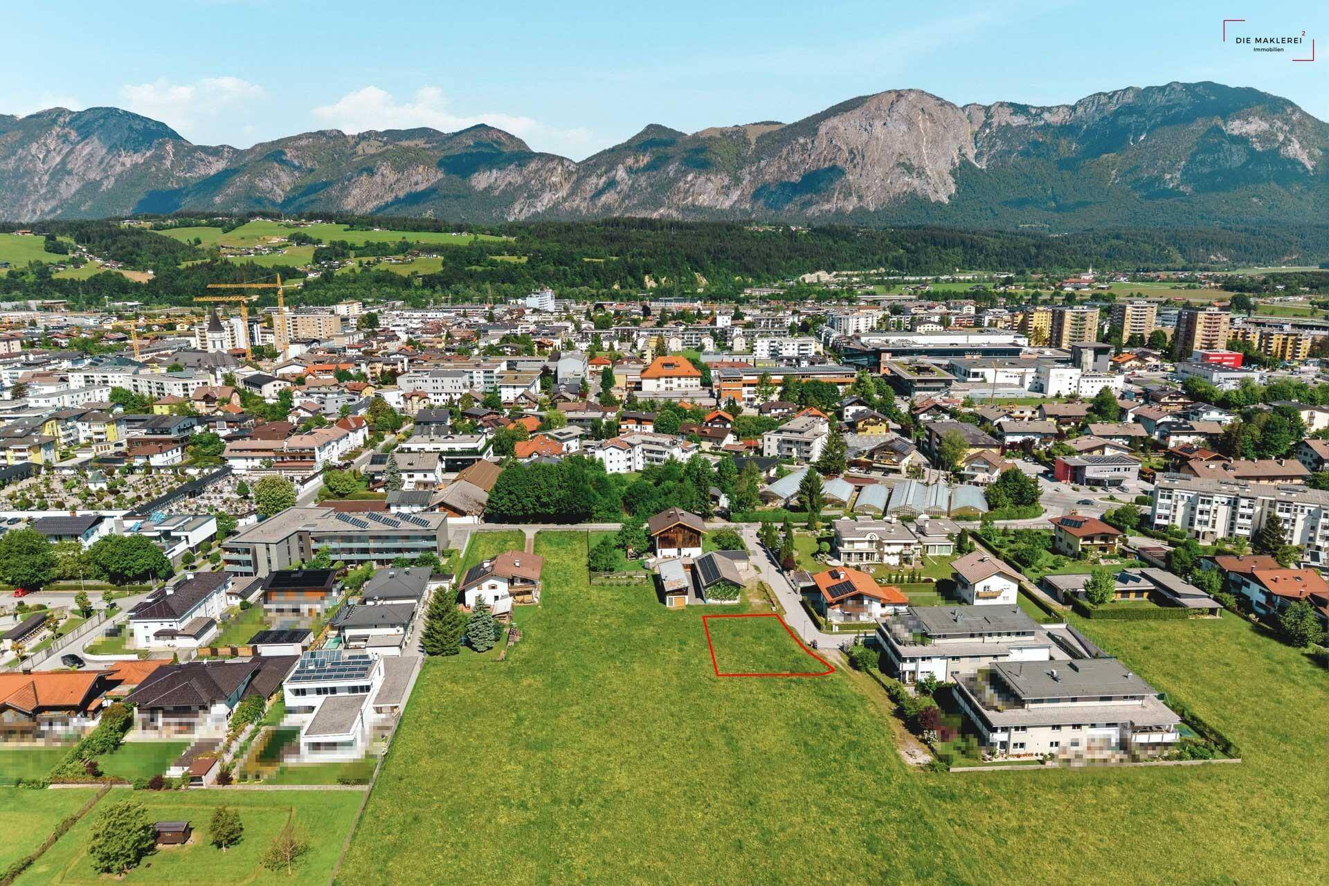 Luftaufnahme eines freien Grundstücks in einer Wohngegend mit Blick auf die umliegende Bergwelt.