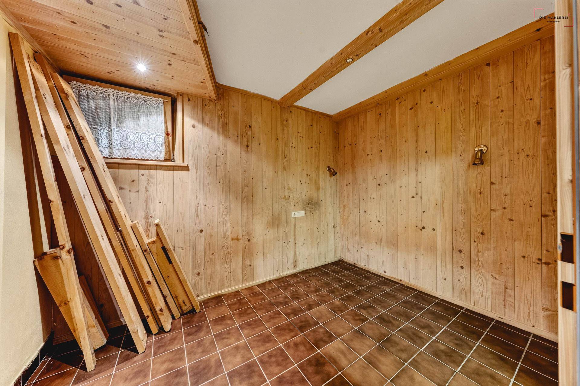 Abstellraum im Keller mit Holzverkleidung, gefliestem Boden und kleinem Fenster.