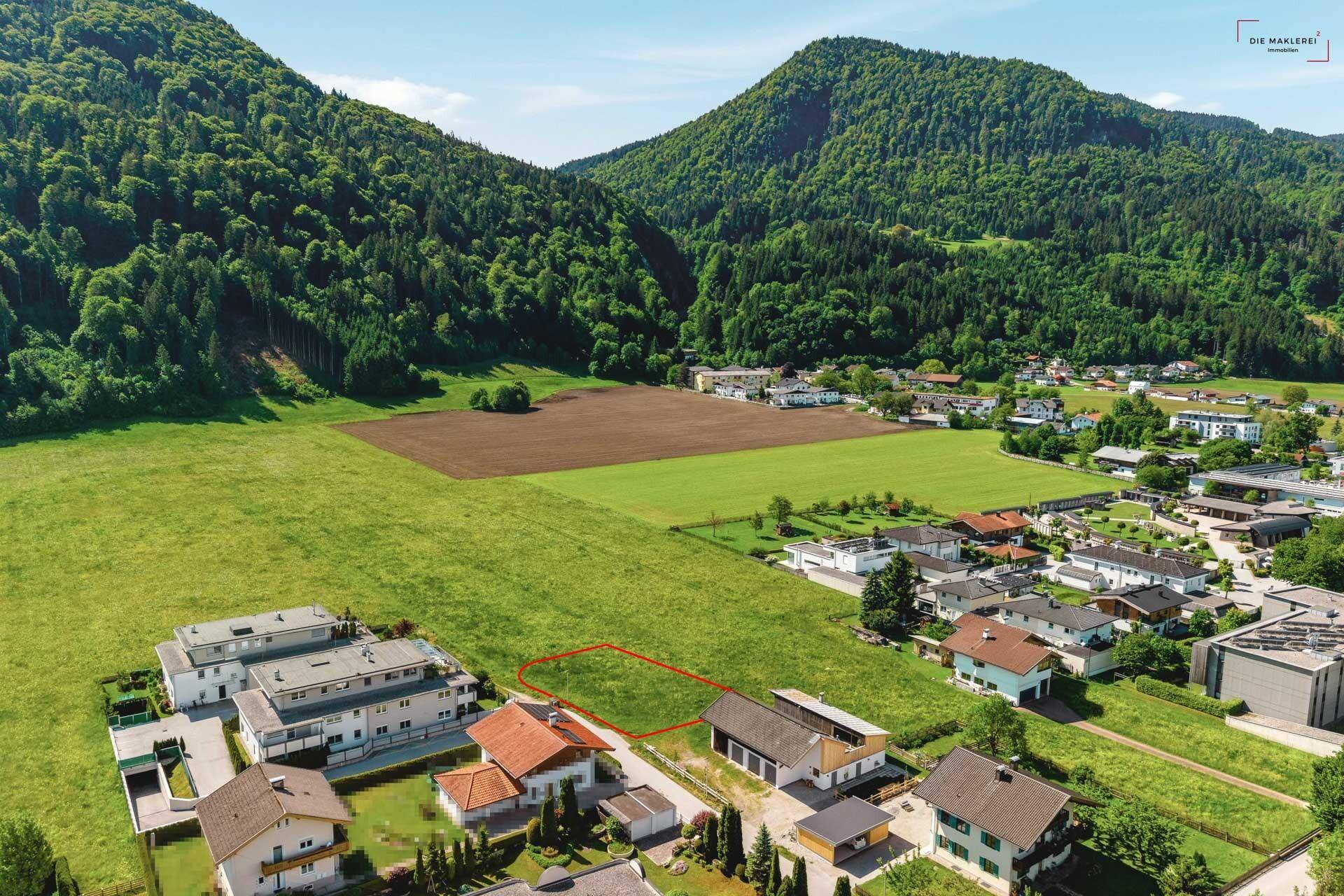 Luftbild eines Baugrundstücks in einer idyllischen Umgebung mit weiten Feldern und bewaldeten Hügeln.