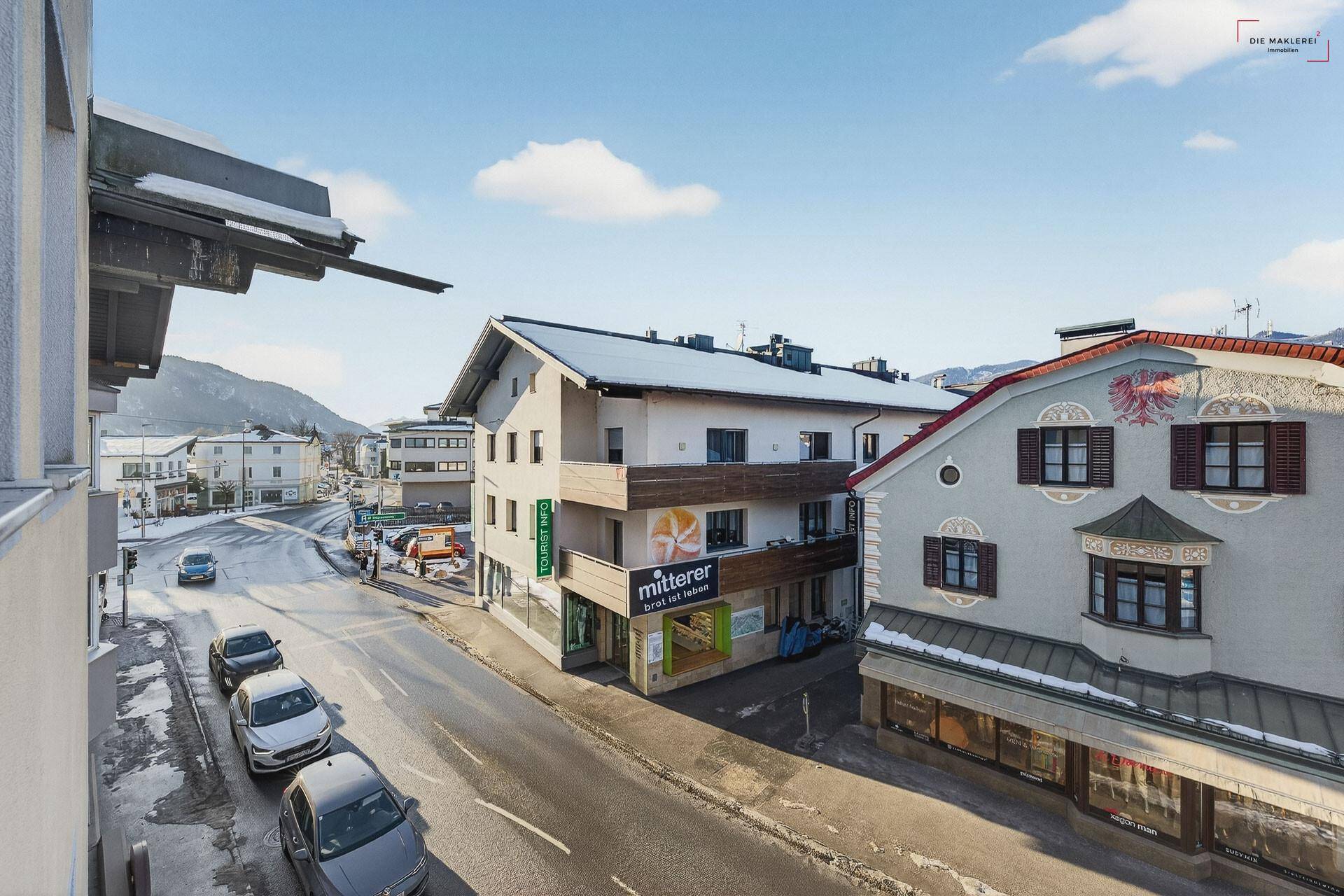 Blick von oben auf die belebte Straße mit parkenden Autos und umliegenden Gebäuden in der Stadt.