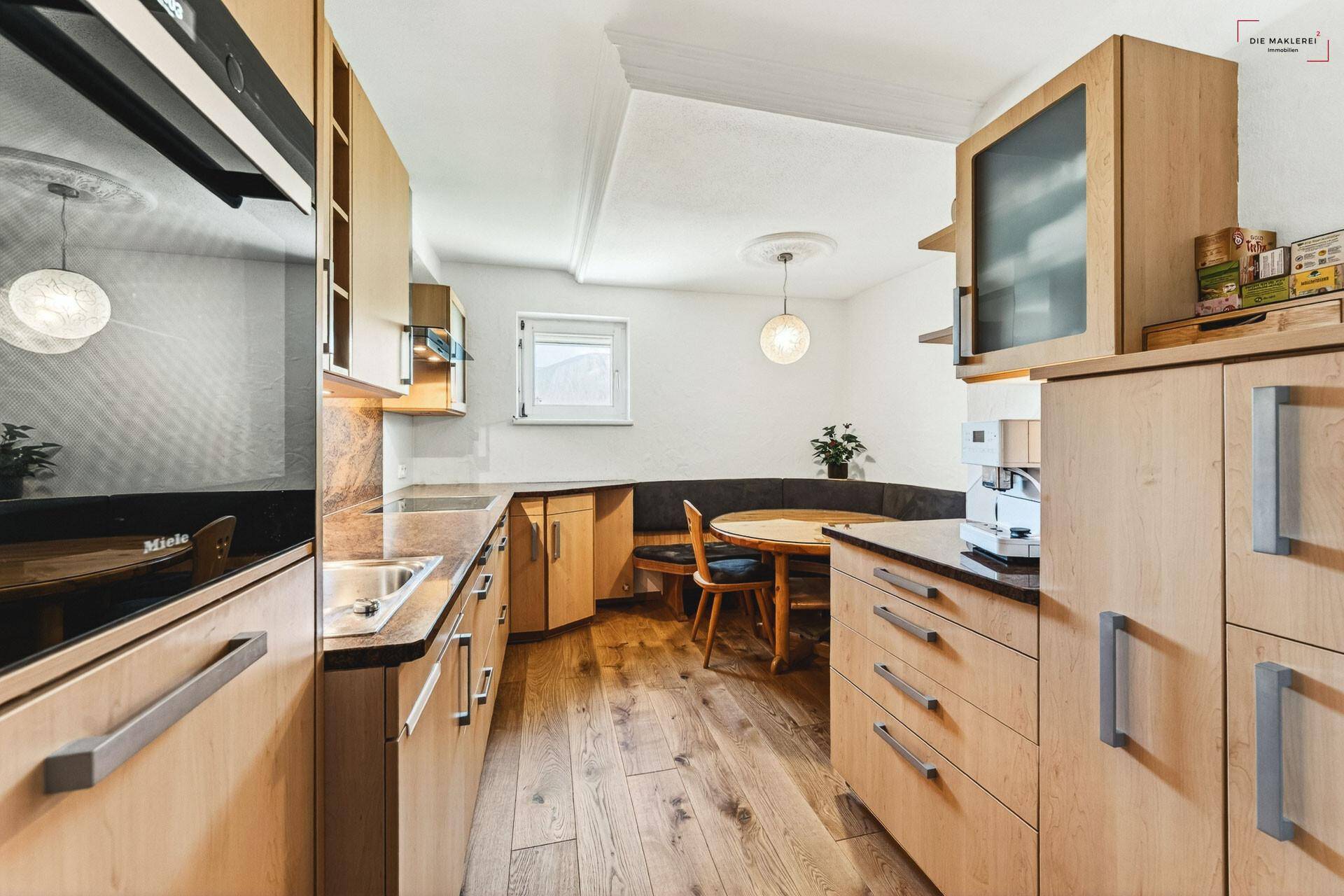Funktionale Küche mit Holzschränken, Granitarbeitsplatten und gemütlicher Essecke.