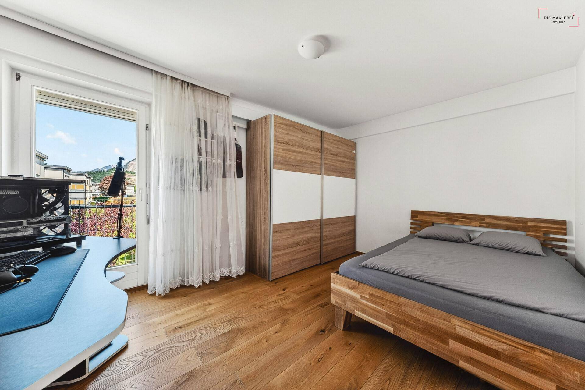 Schlafzimmer mit Holzbett, Schiebetürenschrank und direktem Zugang zum Balkon.