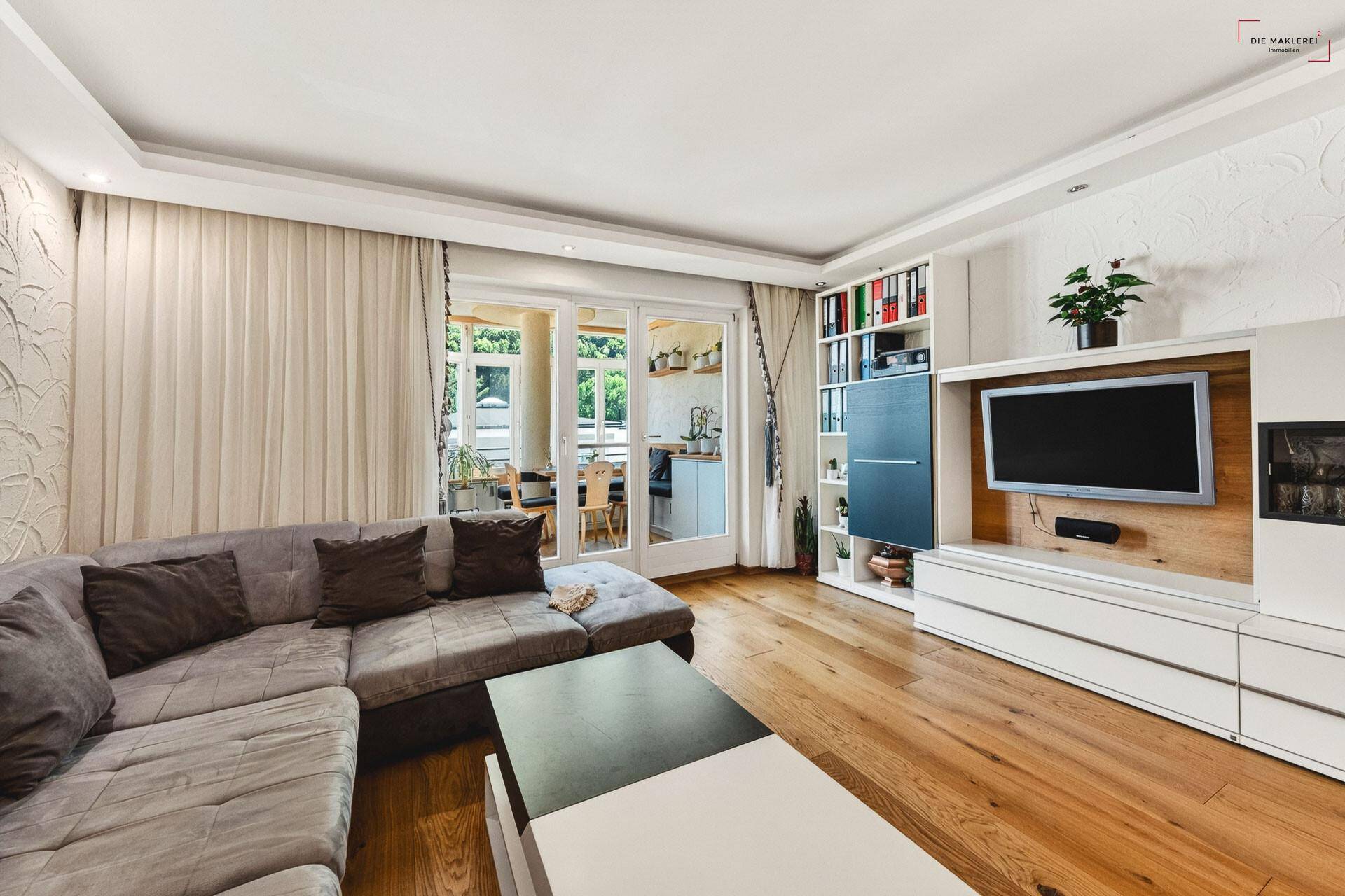 Gemütliches Wohnzimmer mit großem Sofa, TV-Möbel und Zugang zu einem weiteren Raum.