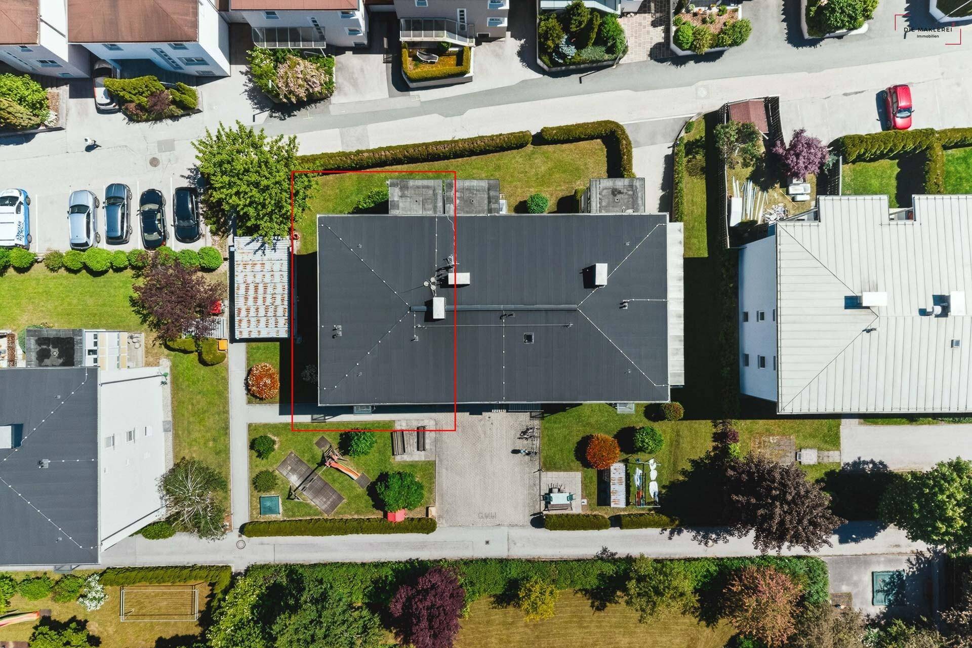 Dachansicht des Wohngebäudes mit umliegenden Gärten und Parkplätzen.