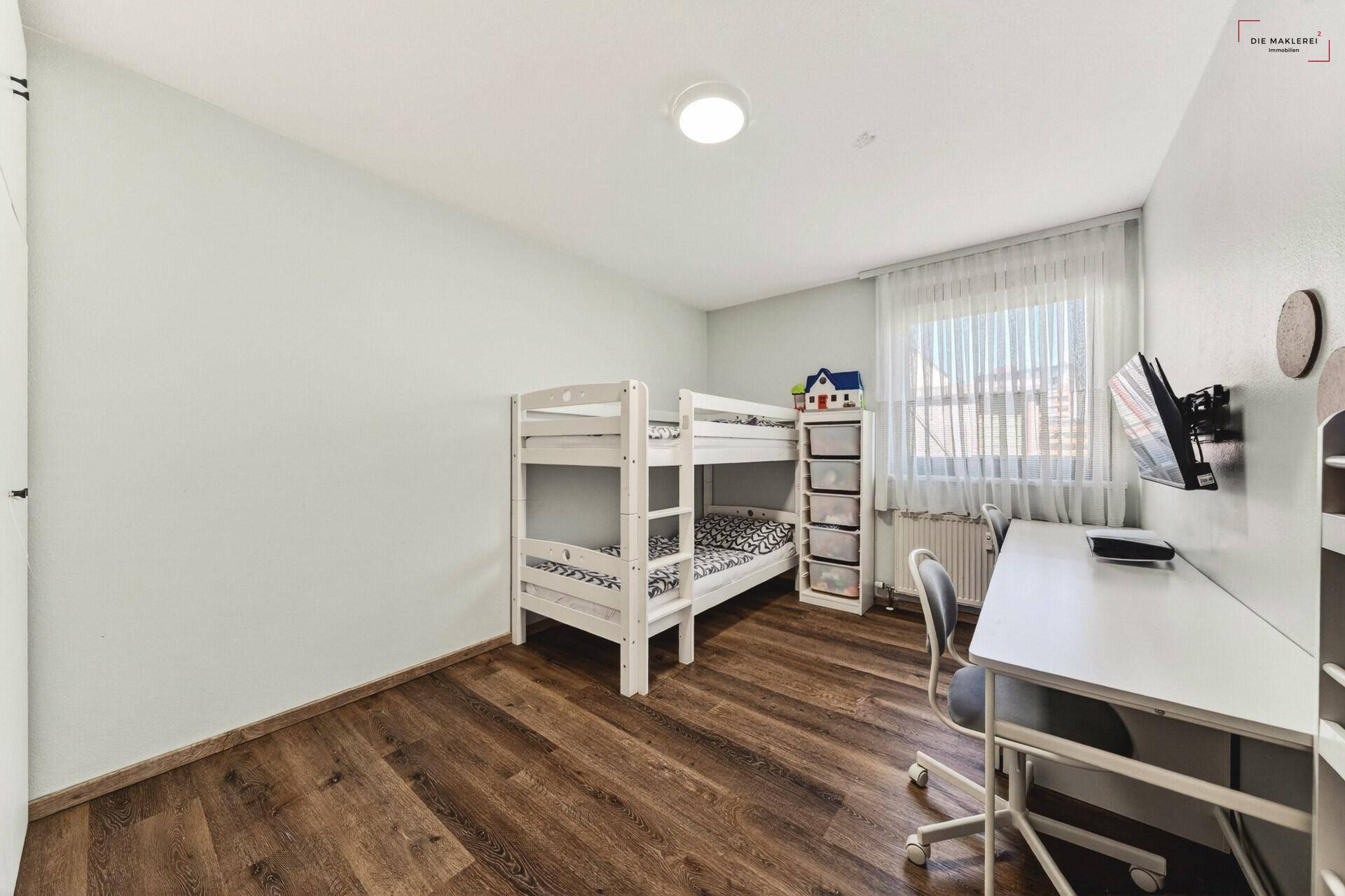 Kinderzimmer mit Etagenbett, Schreibtisch und Holzboden, hell und funktional eingerichtet.