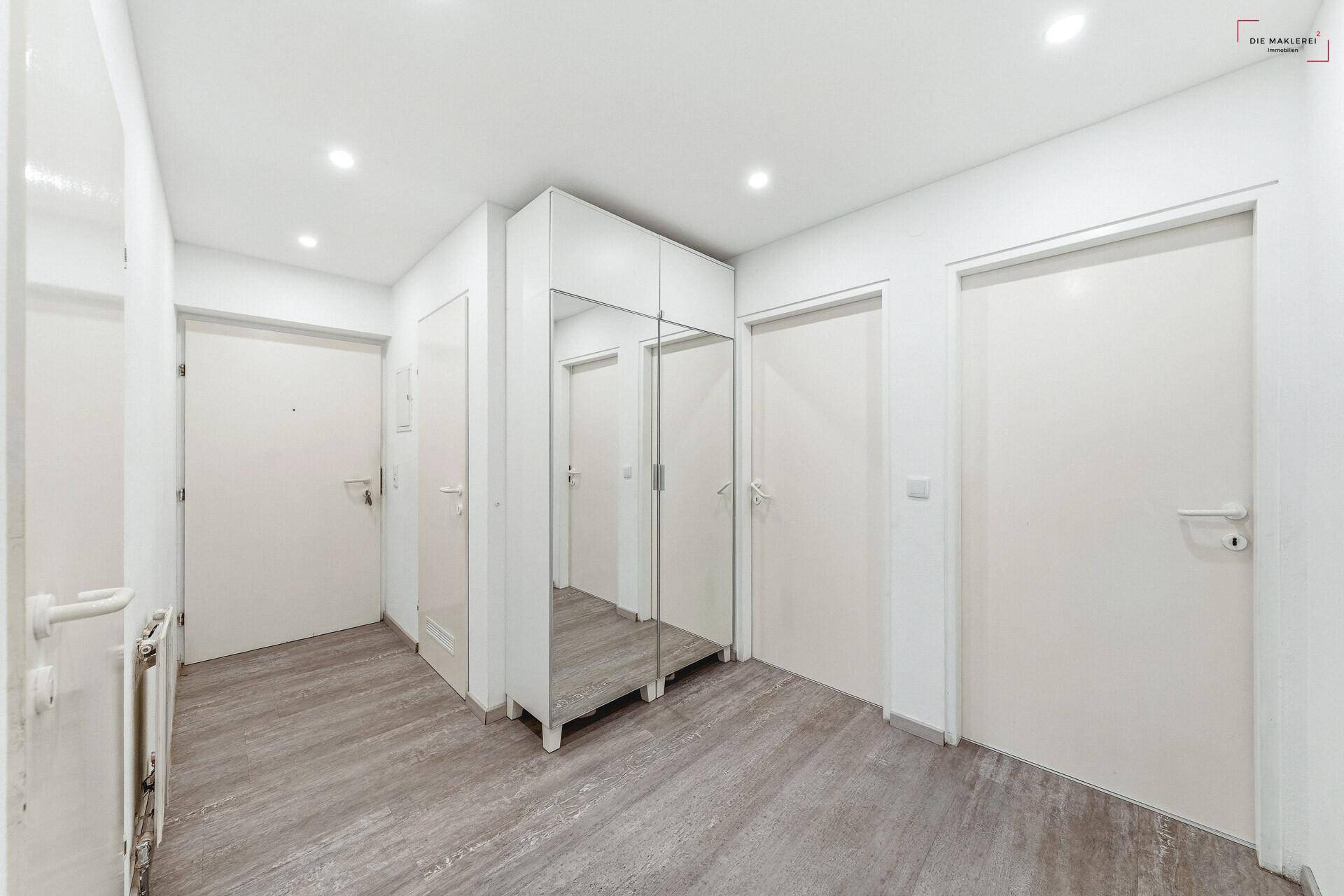 Heller Flur mit modernem Spiegelschrank und hellem Laminatboden, bietet viel Stauraum.