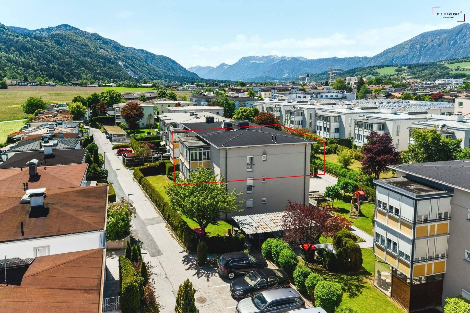 Luftaufnahme eines Wohngebäudes in einer städtischen Umgebung mit Bergpanorama.