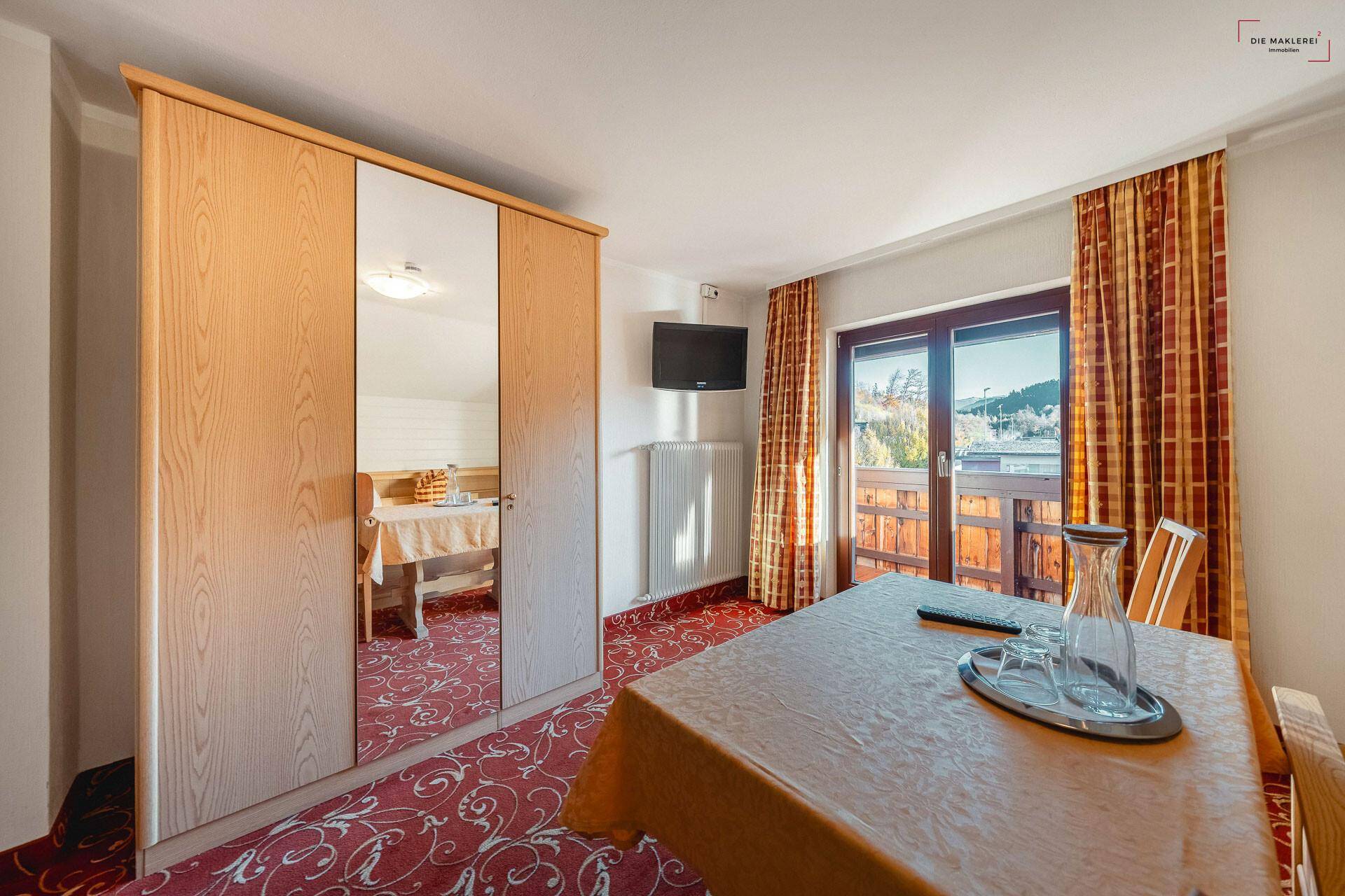 Helles Schlafzimmer mit Teppichboden, Kleiderschrank und Balkonzugang mit Blick ins Grüne.