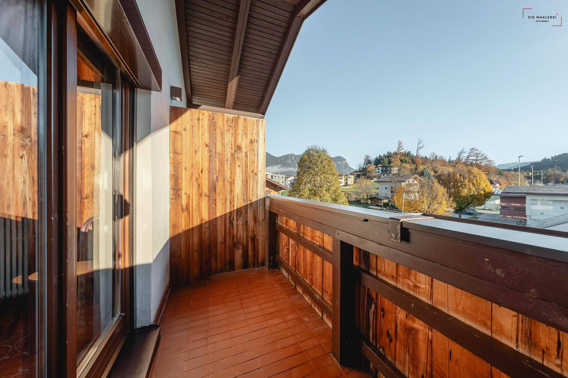 Kleiner Holzbalkon mit Blick auf die umliegende Landschaft und die Berge im Hintergrund.