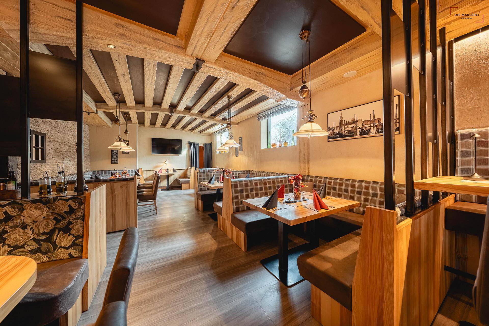 Gemütlicher Restaurantbereich mit Holzbalken, gepolsterten Sitzgelegenheiten und warmem Licht.