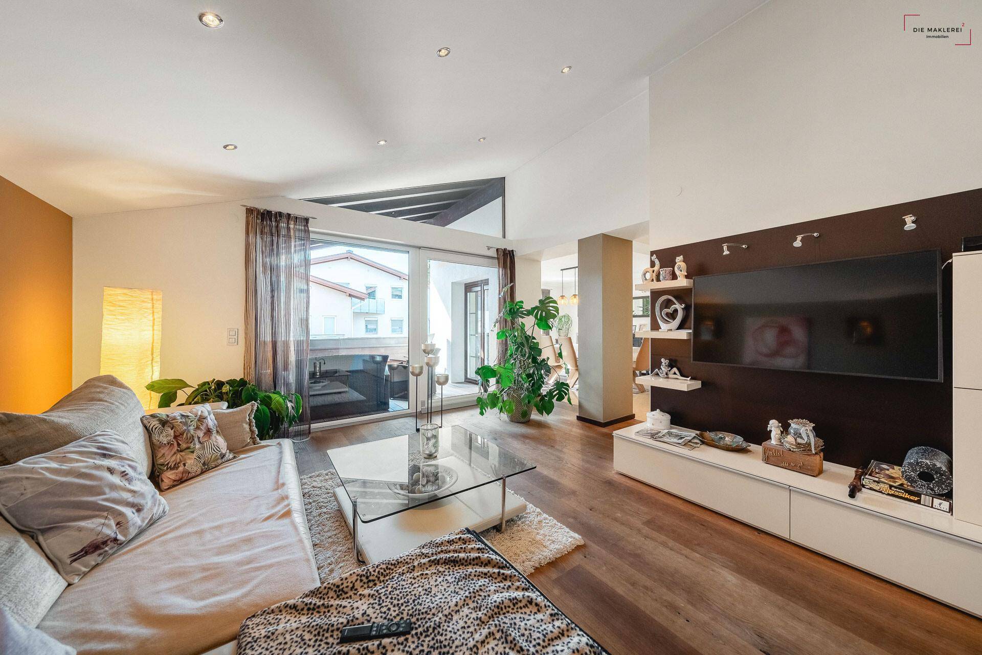 Geräumiges Wohnzimmer mit Holzboden, viel Tageslicht und direktem Zugang zu einem Außenbereich.